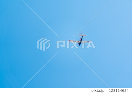 Small ultralight airplane with overhead wing and single propeller flying in sunset sky. 128114624