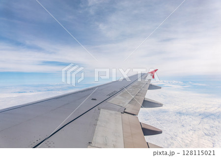 View from the airplane window at a beautiful cloudy sky and the airplane wing 128115021