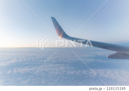 Beautiful salmon dawn and the wing of an airplane above the clouds. 128115195