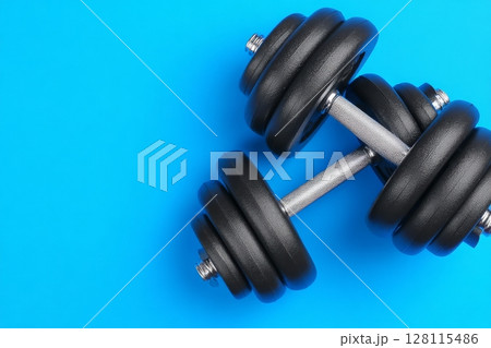 Fitness and exercise concepts are embodied by the various workout equipment, including metal weights and dumbbells, arranged on a blue exercise mat 128115486