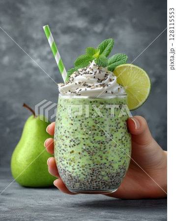 Close-up, a female hand inserts straws into a spinach smoothie cocktail, which is prepared with banana, pear, chia and sesame seeds, and microgreens, in a glass beaker 128115553