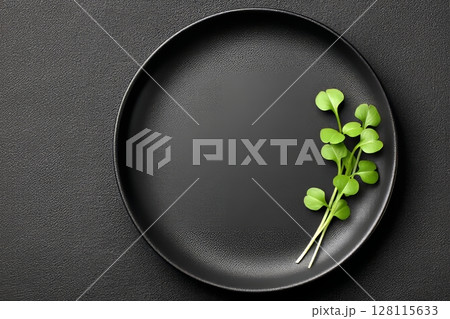 On a black background, a green plate holds a selection of fresh microgreen sprouts 128115633