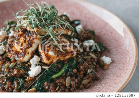 A light background provides the setting for a pink bowl filled with a nutritious vegan salad of peas, microgreen sprouts, and sprouted beans 128115697