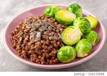A healthy vegan salad consisting of peas, microgreen sprouts, and sprouted beans is placed in a pink bowl on a light background 128115698