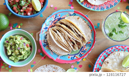 Cinco de Mayo tacos presented with traditional Mexican garnishes, background 128116727