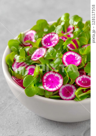 Weiße Schale mit Brokkoli Mikrogreens in Keimsprossenform, die vor einem weißen Hintergrund im Portraitformat arrangiert sind 128117358