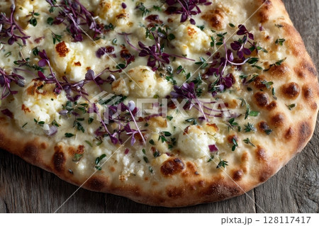 A close-up horizontal shot of a hearty and healthy pizza featuring cheese and a fresh mix of micro greens 128117417