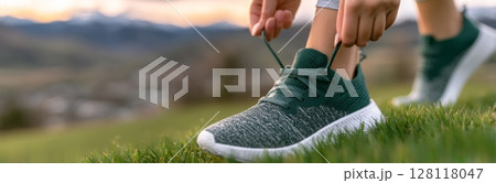 A woman runner is tying her shoelaces in preparation for an autumn jog through a forest park, as depicted in a panoramic banner with copy space, symbolizing exercise motivation and health and fitness 128118047