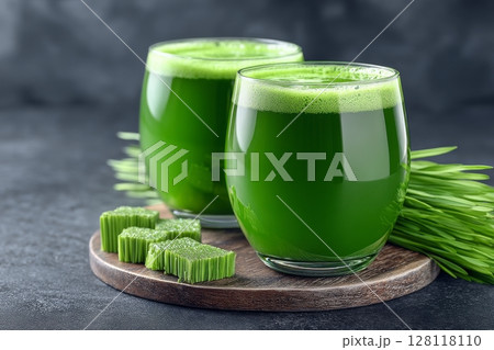 Two shots of green barley grass are situated on a wooden background 128118110