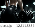 This conceptual image showcases an attractive young woman using dumbbells to work out in a fitness gym, symbolizing a healthy lifestyle 128118284