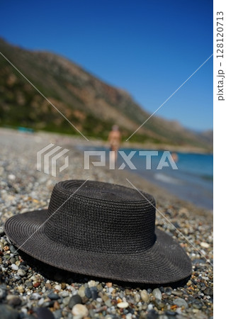Straw Hat on Pebble Beach with Blurred Background 128120713