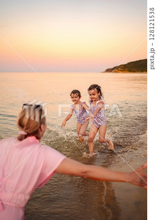 Joyful family moments on the beach at sunset 128121538