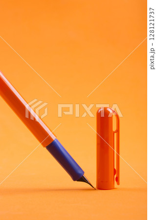 Fountain pen with a cap on an orange background 128121737