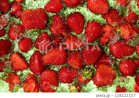 Whole Strawberry Dropped into Water. Splash Effect and Vibrant Summer Look. 128122157
