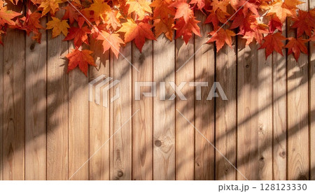 アンティークウッドに赤や橙の紅葉影を薄く重ねたシームレス背景 128123330