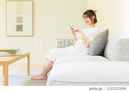 ソファーでスマホを使う女性 ソファーでスマホを使う女性 128123509