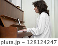 A person is beautifully playing the piano in a cozy indoor setting, exuding warmth A person is beautifully playing the piano in a cozy indoor setting, exuding warmth 128124247