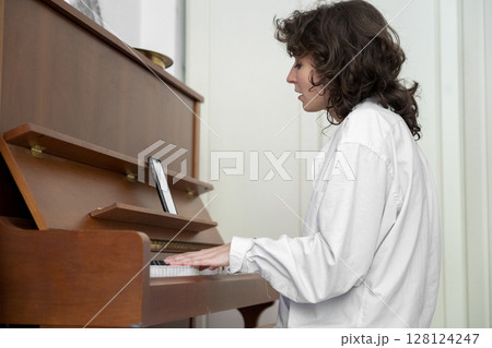 A person is beautifully playing the piano in a cozy indoor setting, exuding warmth 128124247