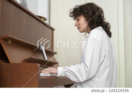 A Young Musician Ensemble Skillfully Playing the Grand Piano in a Cozy and Inviting Setting 128124248