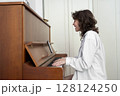 A person is energetically playing the piano while dressed in casual, comfortable attire A person is energetically playing the piano while dressed in casual, comfortable attire 128124250