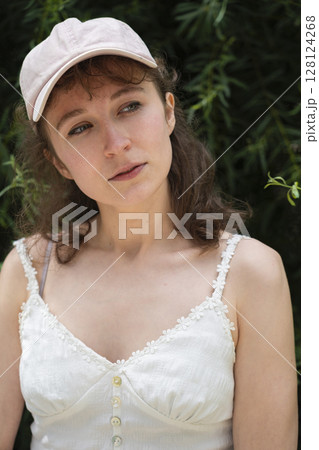 A woman in a stylish summer outfit and cap enjoys the beauty of nature around her 128124268