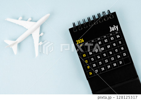 July 2026 black calendar and airplane toy on blue color background. July 2026 black calendar and airplane toy on blue color background. 128125317