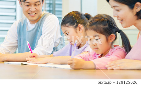 勉強する子供たちと見守るケアスタッフ 128125626