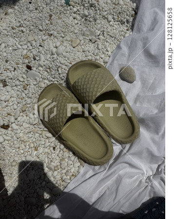 Green Sandals on Beach Towel by White Pebbles 128125658