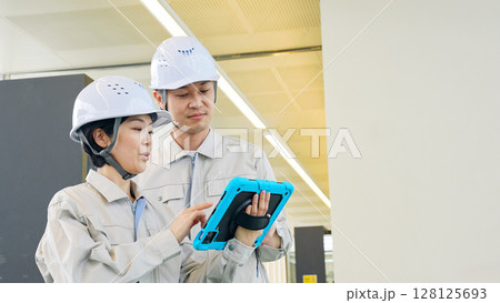 タブレットPCを持ってビルの屋内に立つ男女エンジニア 128125693