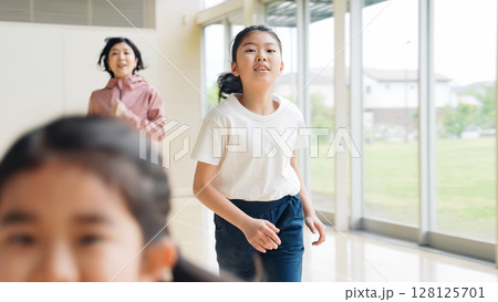 体育館の中を走る女の子と女性教師 128125701