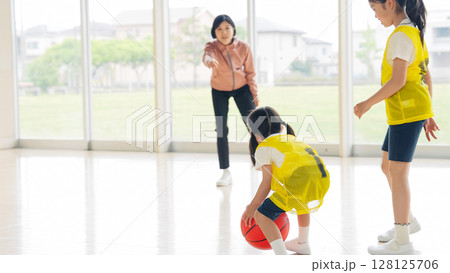 バスケットボールをする子供たちと指導する女性 バスケットボールをする子供たちと指導する女性 128125706