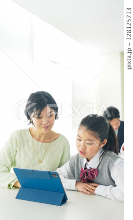 女の子にタブレットを使って指導する女性教師 128125713
