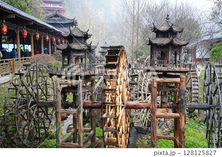 Zhangjiajie, Hunan China. March 12, 2025: Several traditional water wheels installed at the entrance of Huanglong Cave, a famous karst cave in Zhangjiajie, often visited by tourists. Zhangjiajie, Hunan China. March 12, 2025: Several traditional water wheels installed at the entrance of Huanglong Cave, a famous karst cave in Zhangjiajie, often visited by tourists. 128125827