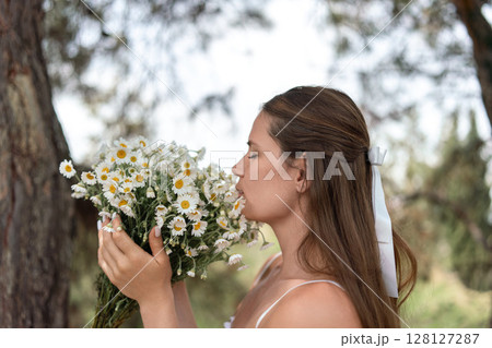 Daisies Bouquet Woman Nature, girl enjoys spring smelling flowers outdoors, serene moment with daisies bouquet. Daisies Bouquet Woman Nature, girl enjoys spring smelling flowers outdoors, serene moment with daisies bouquet. 128127287