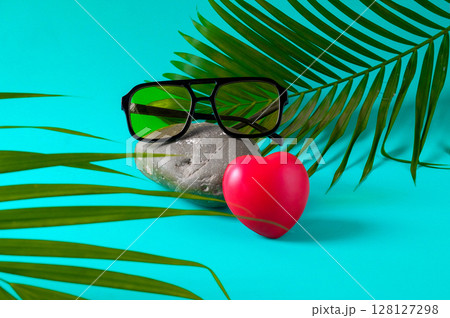 Trendy sunglasses on rock with palm leaves. 128127298