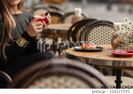 Cafe Coffee Donut, woman enjoys coffee and dessert outdoors in daytime for a relaxing break. Cafe Coffee Donut, woman enjoys coffee and dessert outdoors in daytime for a relaxing break. 128127335