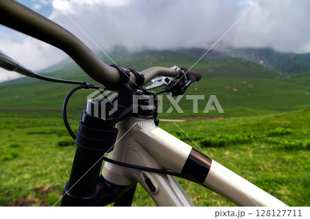 Handlebars of a bicycle against the backdrop of an epic mountain landscape. Mountain bike concept 128127711