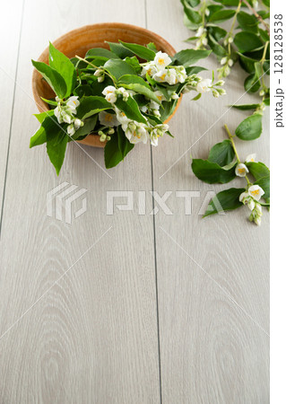 wooden light background and white jasmine flowers 128128538