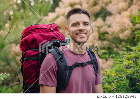 Happy man backpacker smiling in forest during summer hike. Outdoor travel, adventure and active lifestyle concept. Happy man backpacker smiling in forest during summer hike. Outdoor travel, adventure and active lifestyle concept. 128128943