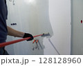 A man paints the inner wall of his house. Apartment renovation. Concrete walls are painted with a paint roller. High quality photo 128128960