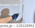Close-up of a hand with a roller. Apartment renovation. Concrete walls are painted gray with a paint roller. High quality photo 128128962