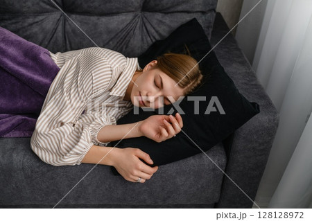 Young woman sleeping peacefully on gray sofa at home. Young woman sleeping peacefully on gray sofa at home. 128128972