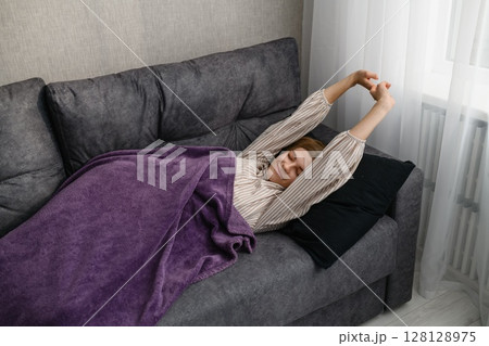 Young woman stretching in bed after waking up at home. 128128975