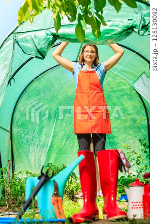 Female farmer and gardening tools in garden 128130092