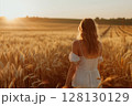 Graceful woman slowly walking through a wheat field at dawn, feeling the connection to nature and open space. 128130129