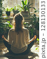 A tranquil top-down view of a woman embracing stillness and breathwork surrounded by soft sunlight and thriving houseplants. 128130133