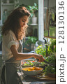 A colorful bowl comes together as a woman combines fresh vegetables in her bright kitchen space 128130136