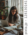 A young woman takes a quiet break, looking up from her screen with tired eyes amid hours of focused study. 128130141