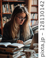 In a quiet academic space, a student cross-references handwritten notes with her laptop, absorbed in concentration. 128130142