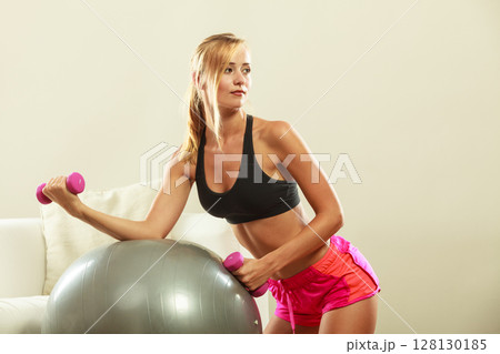 Woman with gym ball and dumbbell doing exercise 128130185